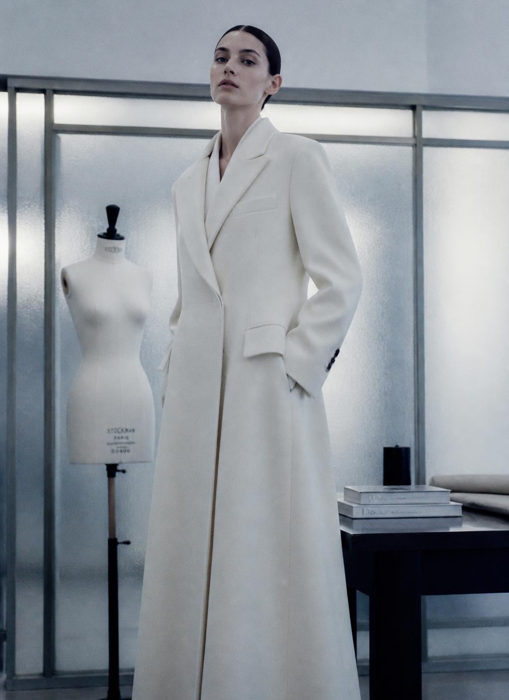 Tall woman being fitted for a tailored coat in a daylit studio